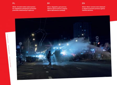 Photograph from the exhibition Belarus. road to freedom. a combat vehicle uses a water cannon to pacify a protest. in the foreground a barricade made of metal railings. night.